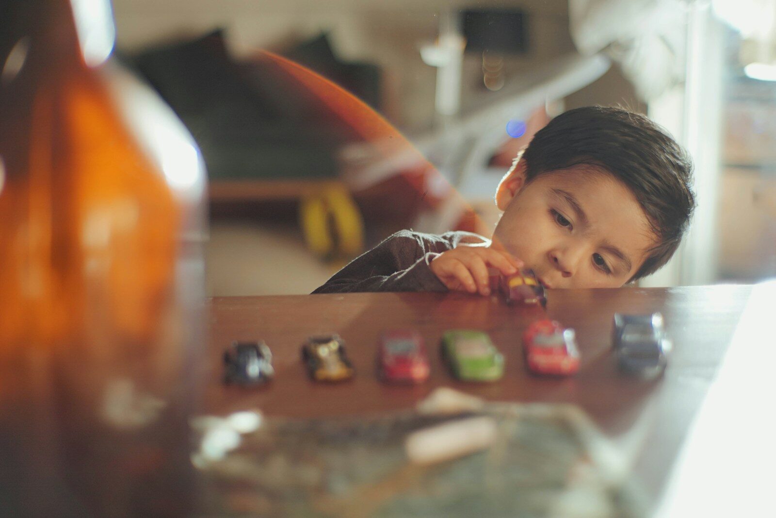 A little boy sitting at a table with a bunch of toy cars on it